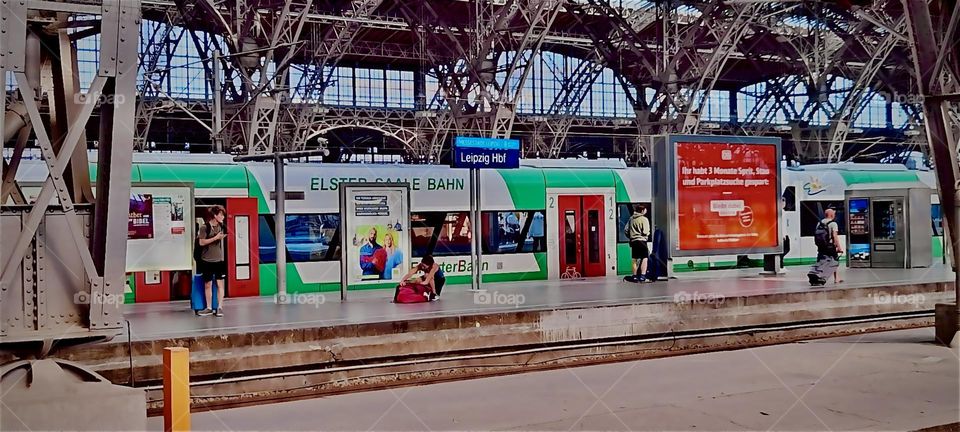 The interior of the “Bad Ülster” train station with advertising billboards lining the train tracks. In the background the metallic structure that upholds the building from the early industrial age can be seen. 2022. Hypnotic Productions