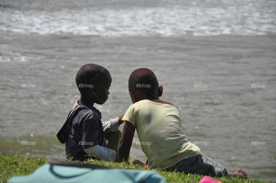 Two African boys sharing lunch next to the ocean in Transkei South Africa