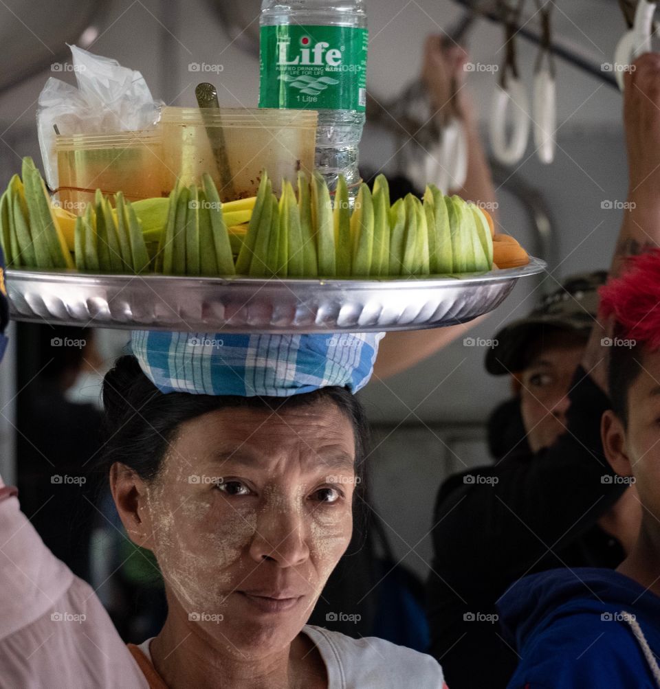 Myanmar woman put mango tray on her head to sell to visitor in train