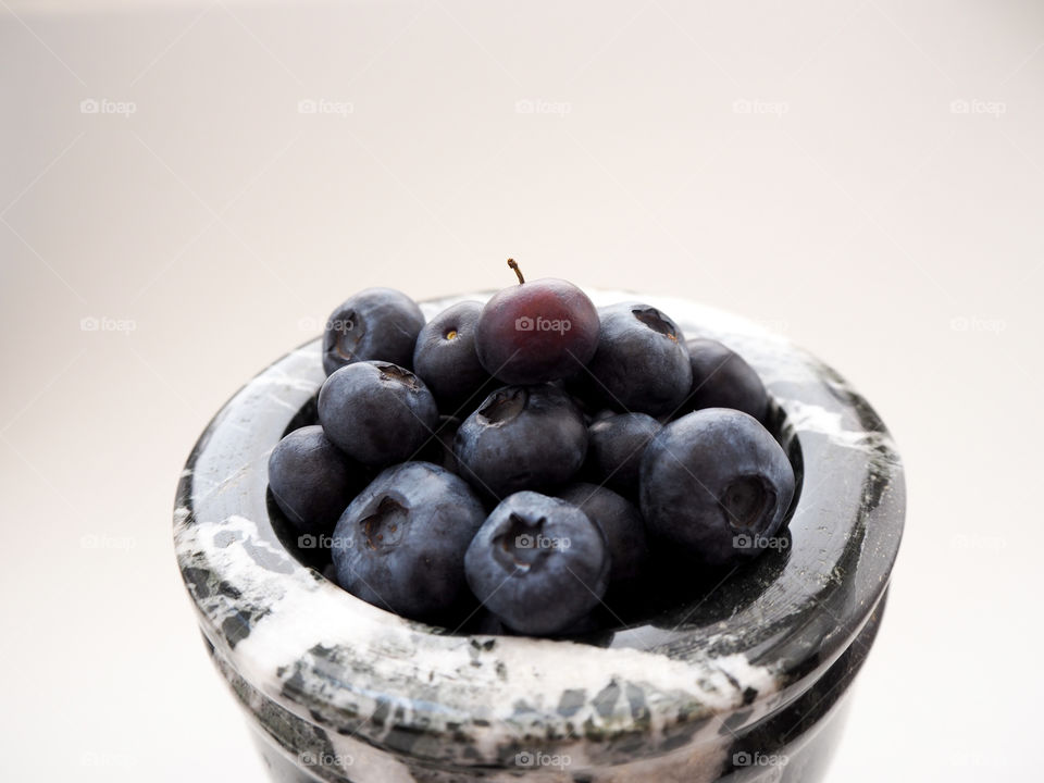 Beautiful bunch of blueberries in a black and white marble bowl.