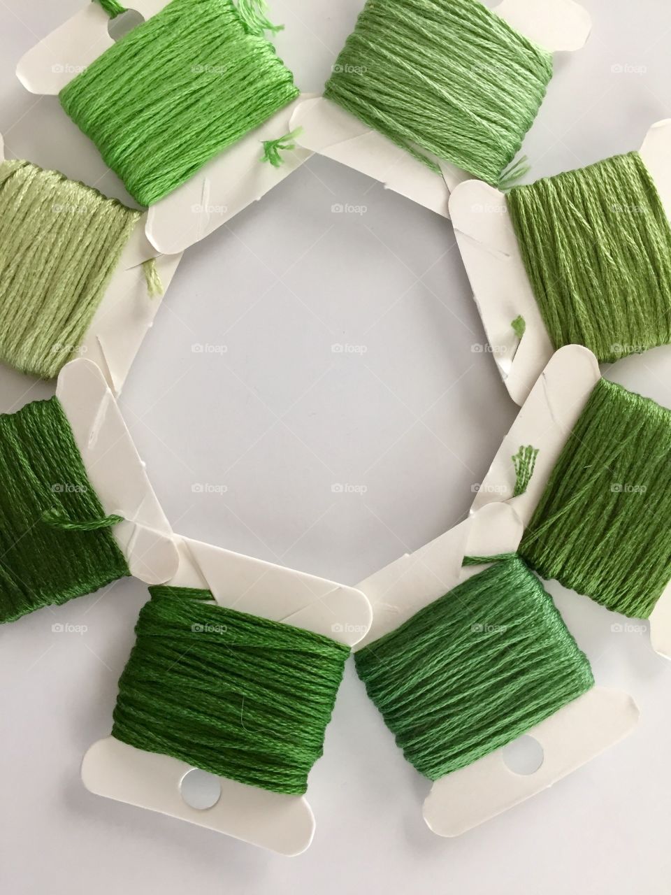 Green Color Story - flat lay closeup of various shades of green embroidery floss / cross stitch thread on paper spools arranged in a circle