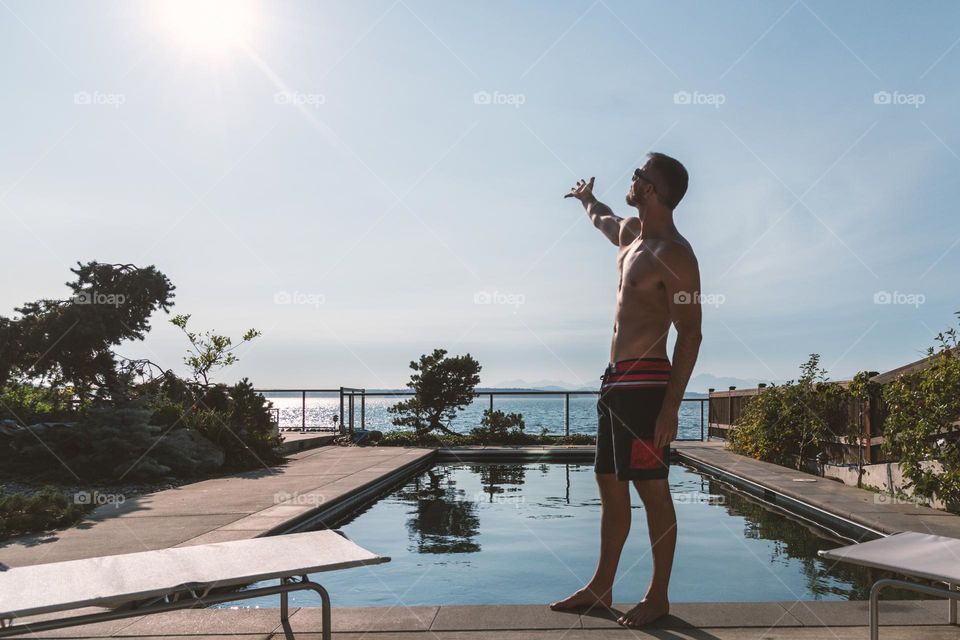 Athletic male poolside welcoming the sun. 