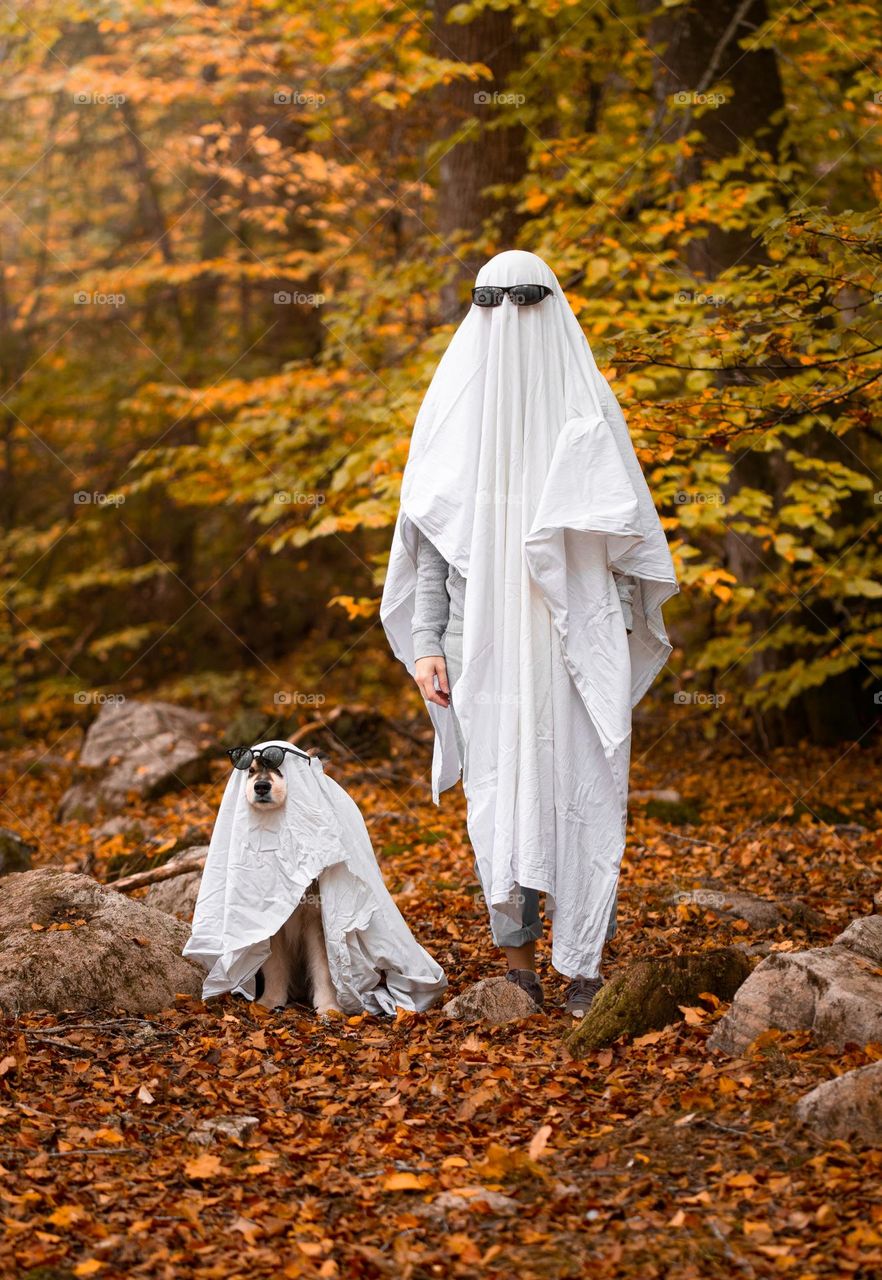 A woman and dog dressed up as ghosts for halloween
