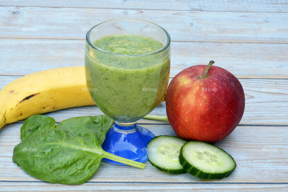 green smoothie with fruit and vegetable,
spinach, banana,apple,cucumber on a wooden background