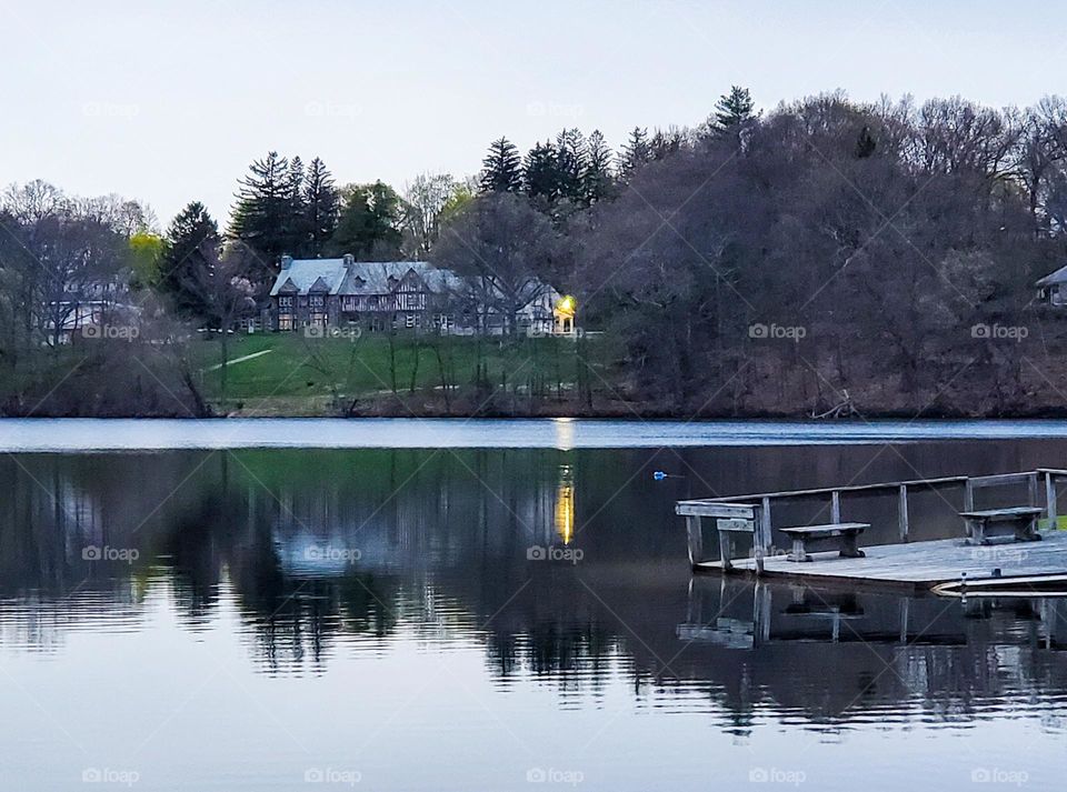 A gorgeous hillside mansion seen from across a very still lake