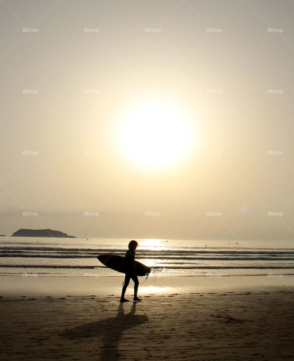 Surfer walking along the beach in Essaouira, Morocco.