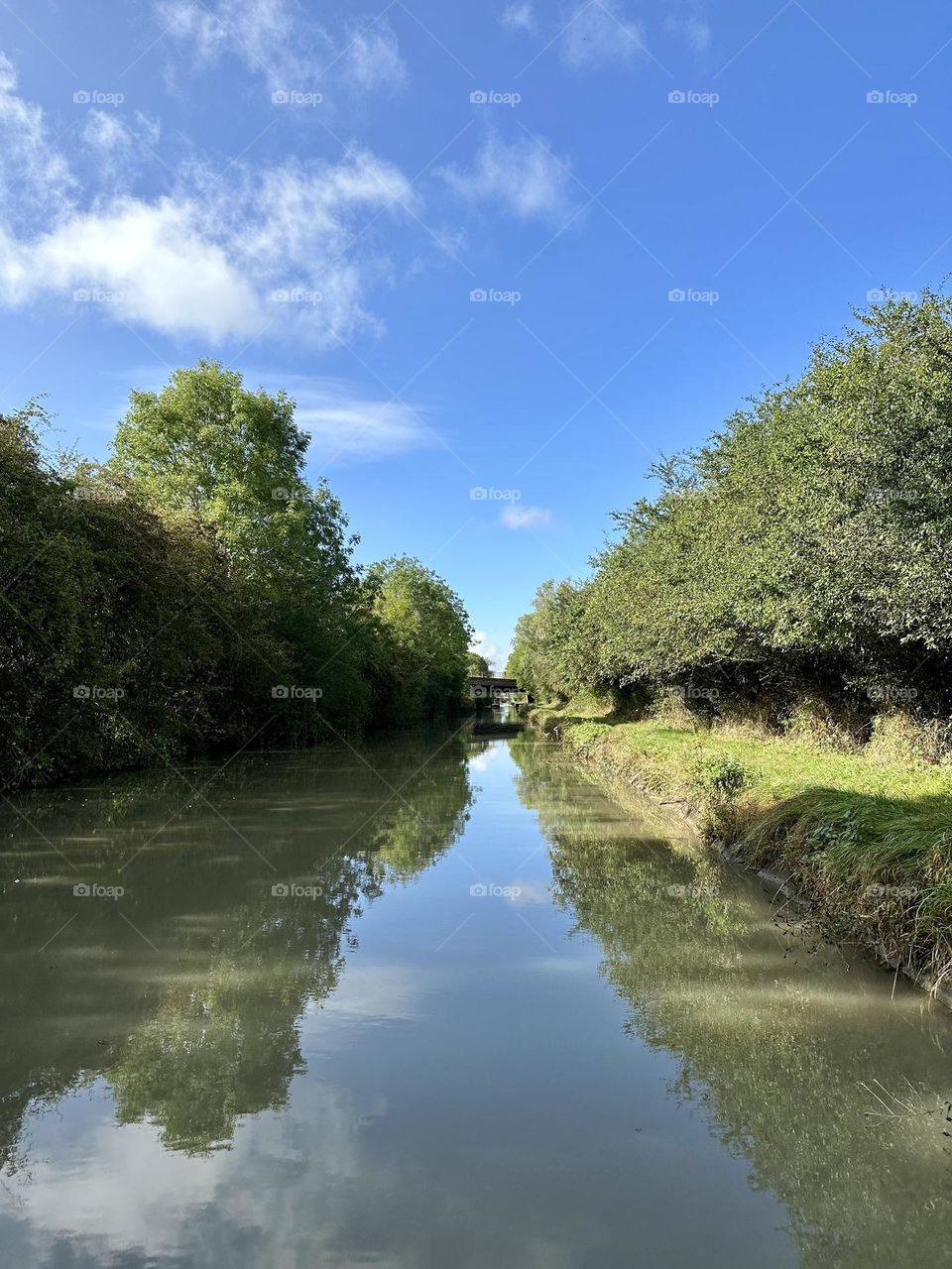 Mid-morning narrowboat cruise on Oxford canal between Barby and Onley clear sunny sky lovely late summer weather vacation holiday English country tree line scenery view water reflections