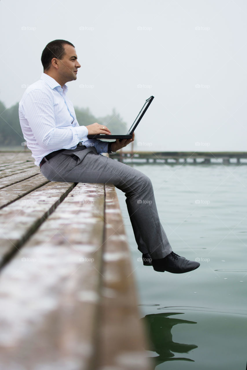 Man on lake dock with laptop