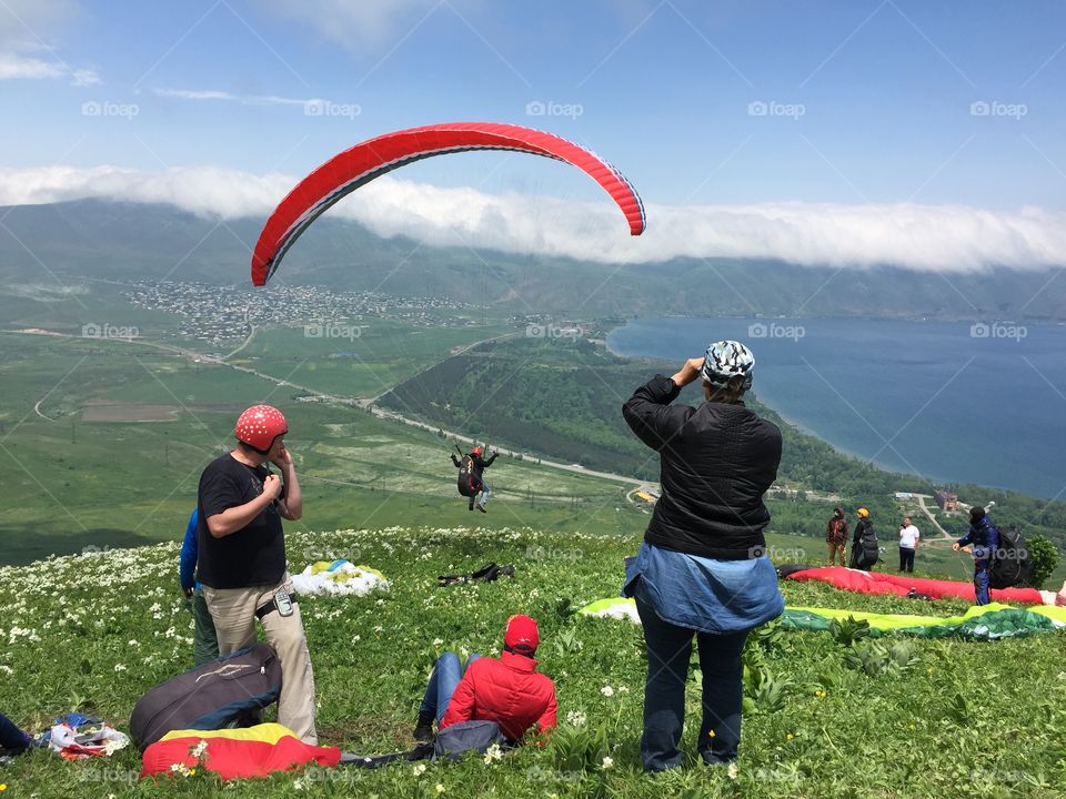 Paragliding with lake view. Paragliding team taking off. 
