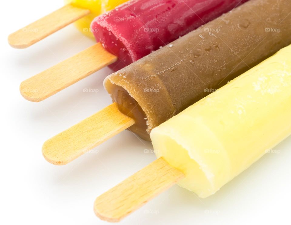 Close-up image of an assortment of ice lollies (popsicles) of different flavours. Wooden sticks. Isolated on a white background