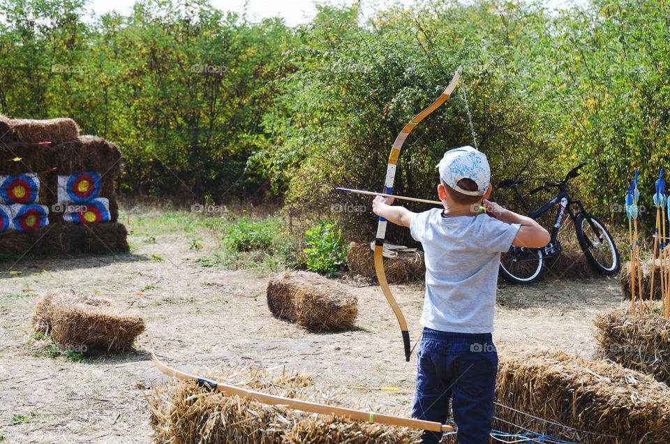 A little boy, a schoolboy shoots a bow at a target.