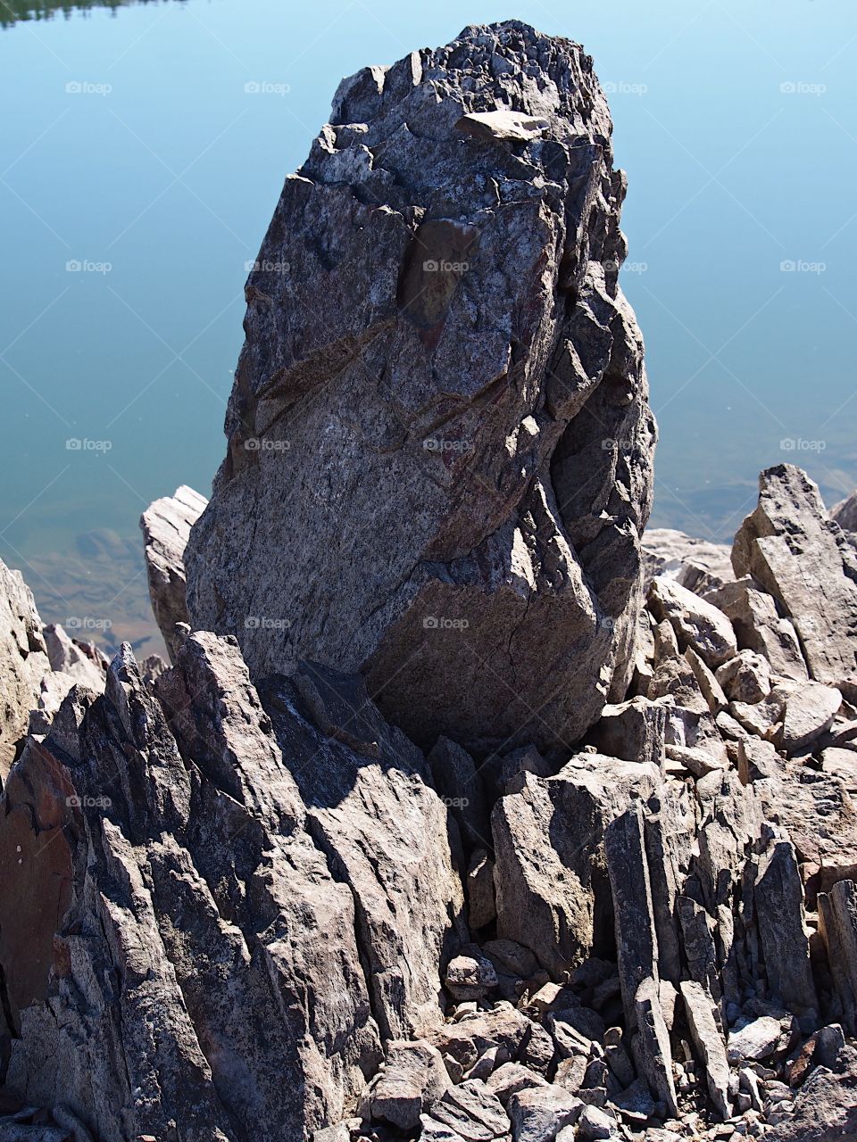 Jagged rocks and boulders along the shoreline of Ochoco Lake in Central Oregon on a sunny spring day.