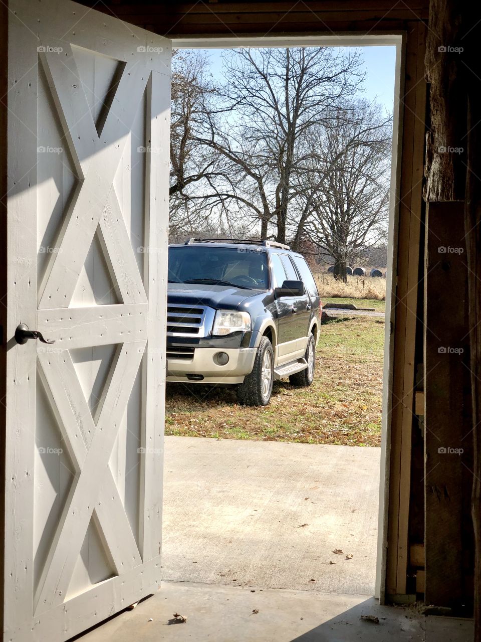 A visit to the old barn. Rustic barn door and vehicle in the country.