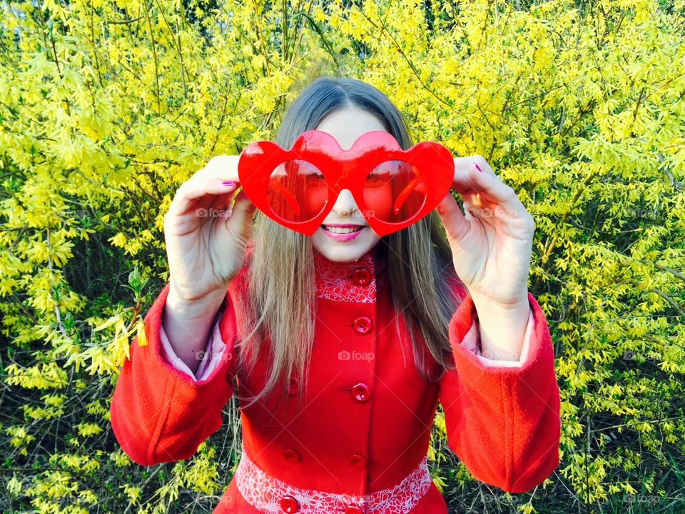 Girl in red with heart sunglasses and yellow flowers in the background