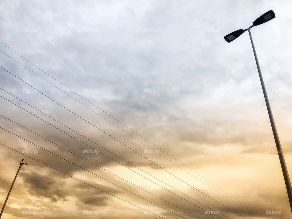 Sky at dawn with yellow clouds, wires and electricity poles