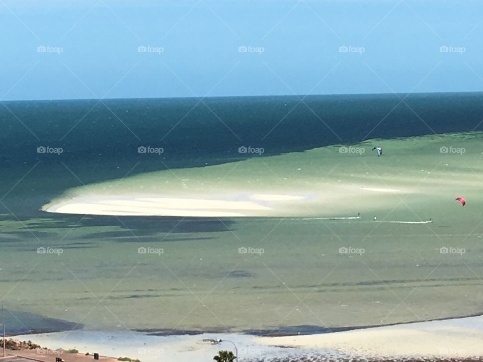 Windy day on remote south Australia beach, kiteboarding boarders sailing along 