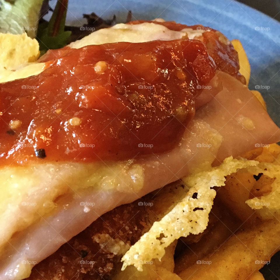 Close-up of chicken parmigiana with chips and green salad. 