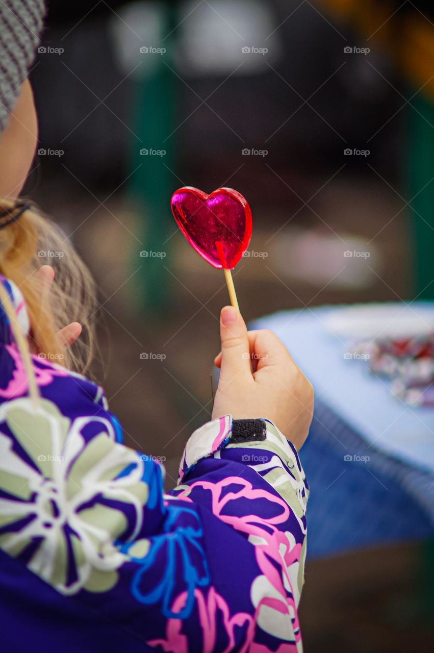 Red lollipop in the form of a heart in the hands of a girl