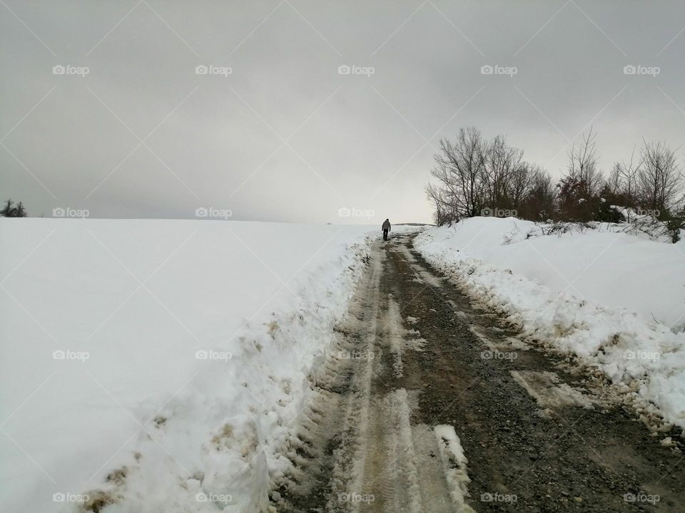 man walking alone in snowy pathway