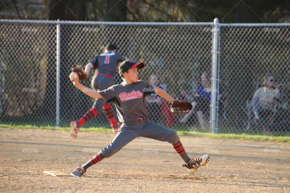 Boy on pitchers mound in baseball game throwing a pitch