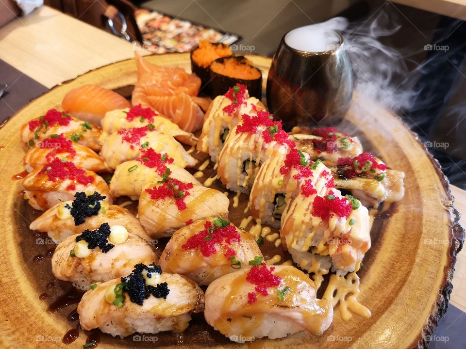 Close-up of burned salmon sushi and roll on wooden plate. Japanese food.