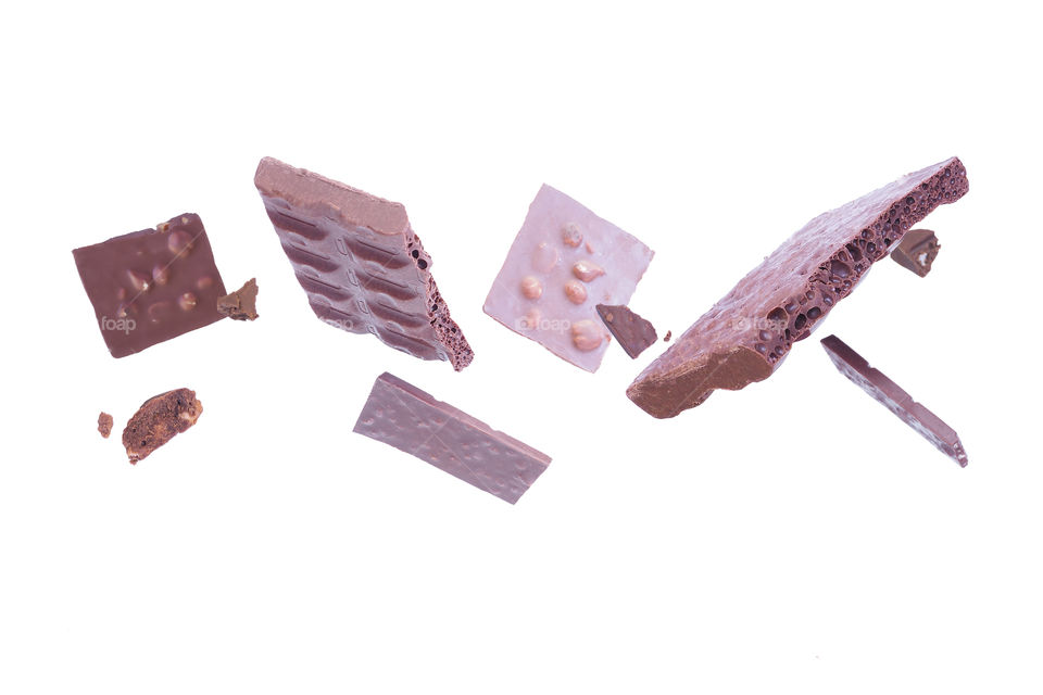 Levitating pieces of broken chocolate on a white background.
