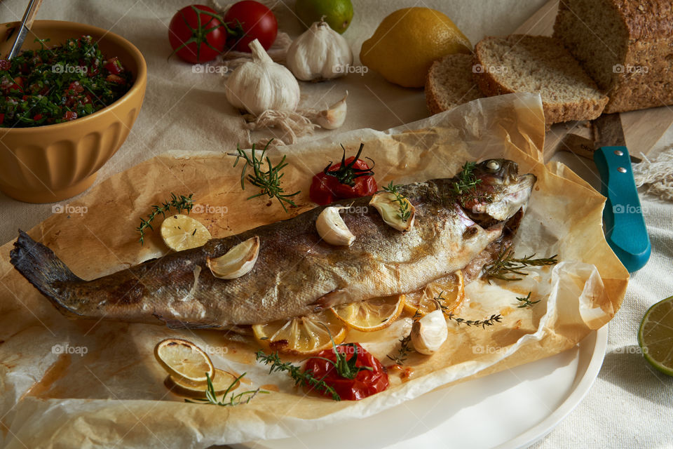 Baked whole trout with garlic, slices of lemon, tomatoes and herbs.