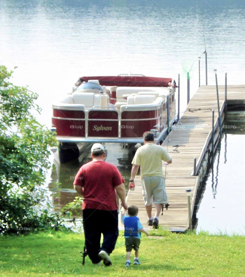 Two men and a little boy walking to the dock to go fishing 