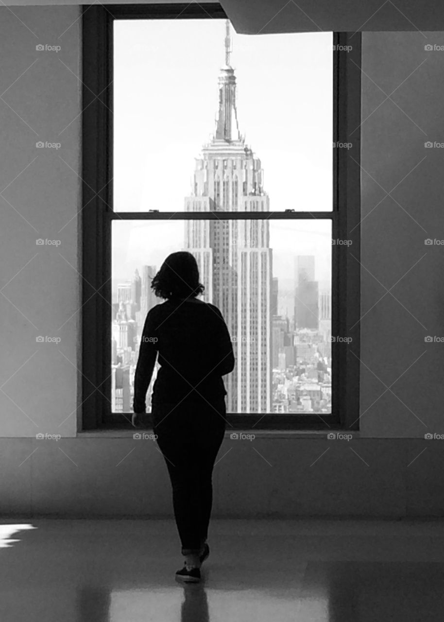 Silhouette of women standing in a window looking at the Empire State Building. Black and white. 