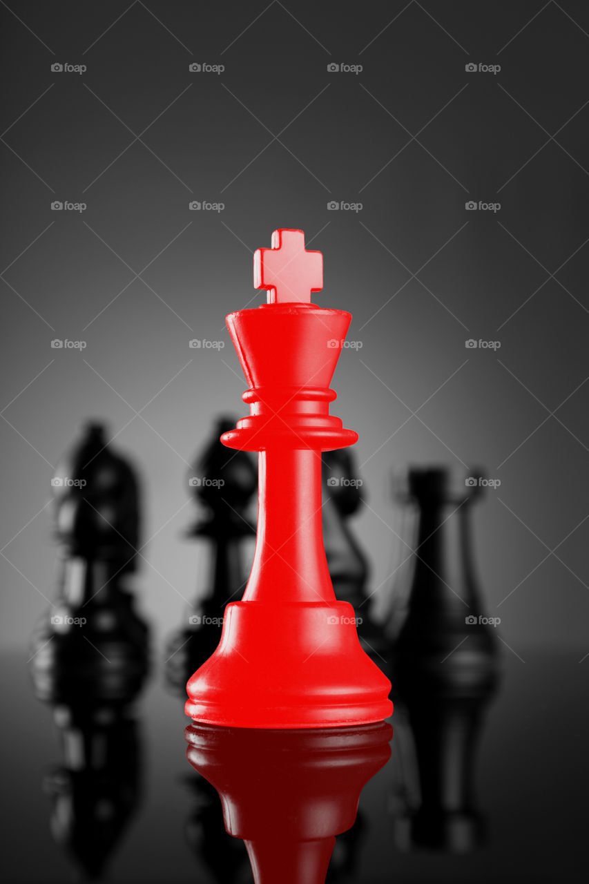 Red chess king with other pieces in black