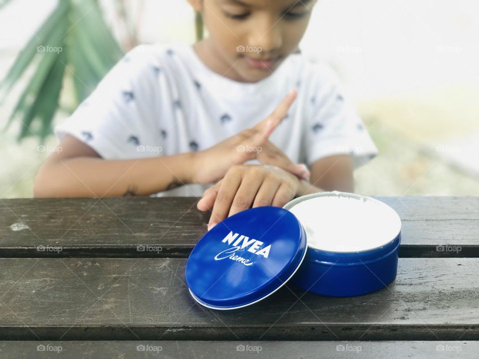 A boy applying Nivea cream to his hand .