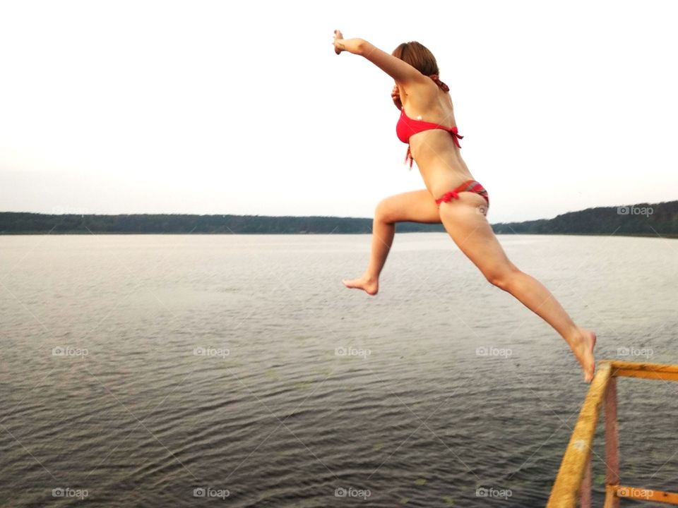 Прыжок девушки в воду с мостика