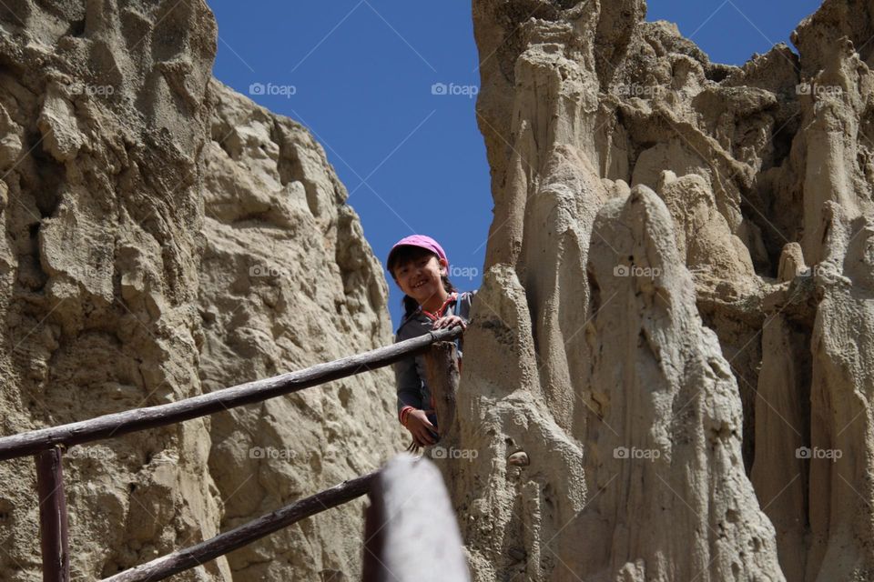 Cute girl is peeking between the rocks