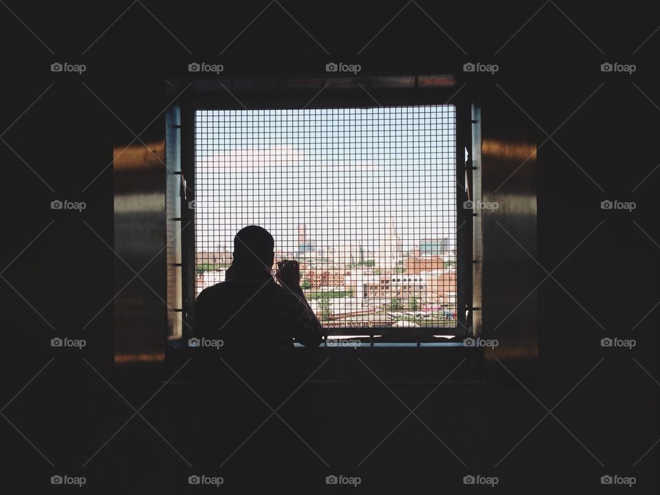 Rear view of man looking through window