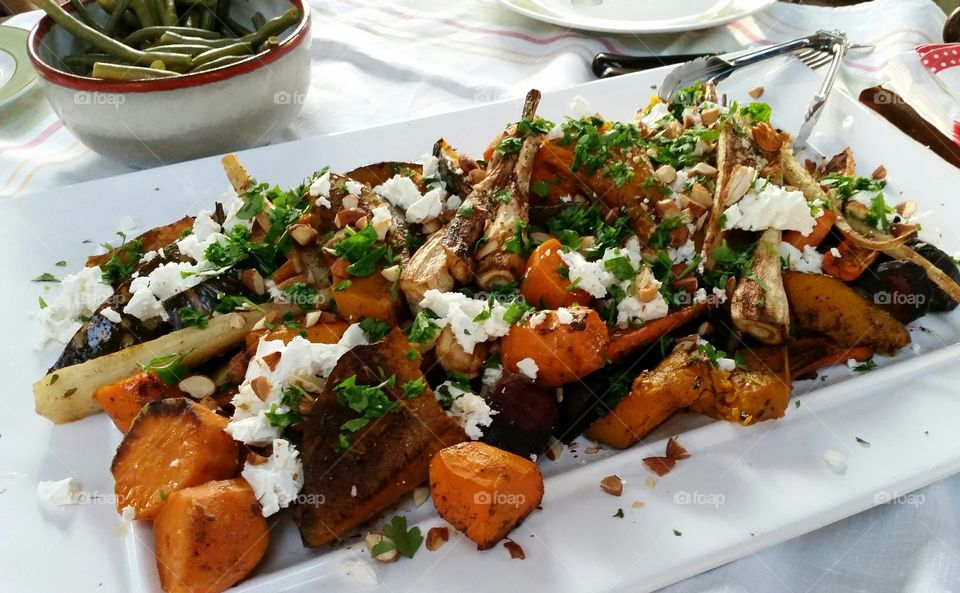 Roasted Vegetables on Platter. A selection of roasted vegetables; carrots, potatoes, parsnips, beetroot and pumpkin basted in red wine and herbs, dressed with almonds and feta cheese.