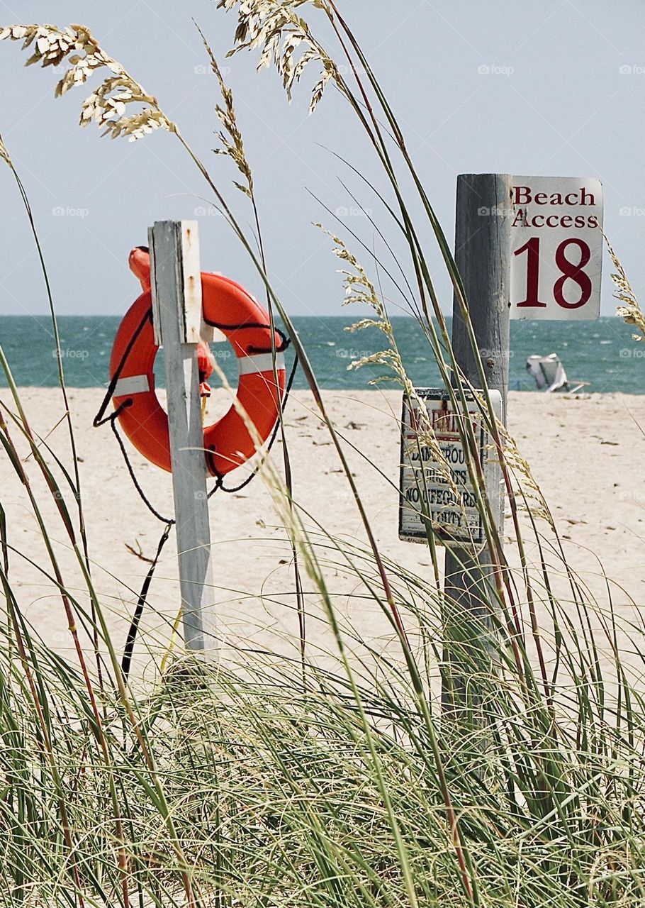 The Atlantic Ocean beckons on a hot summer day, viewpoint from a trail heading towards the sandy shore in North Carolina 