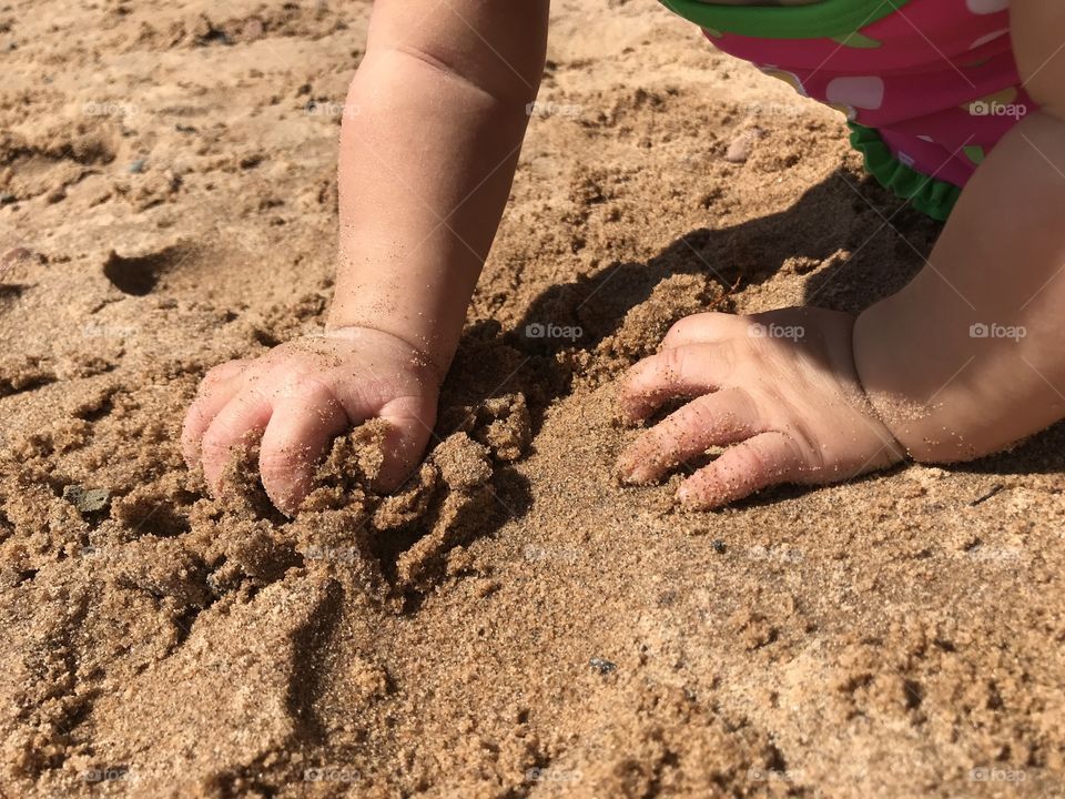 Baby hands grabbing at sand