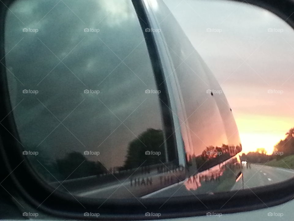 car ride. sunset in the review mirror