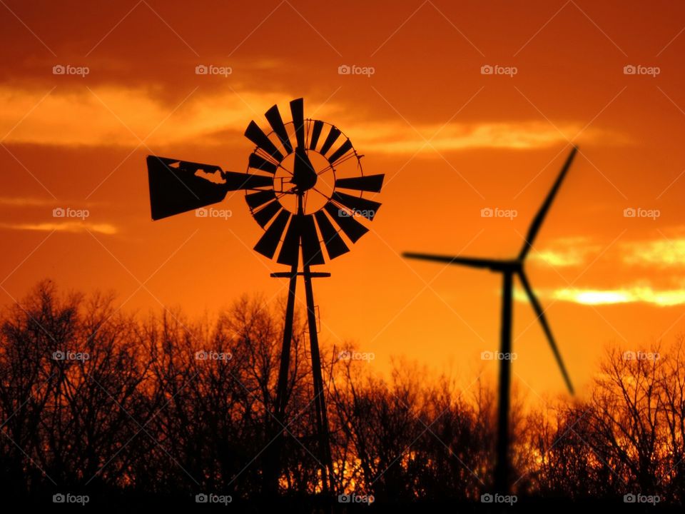 New & Old. An old windmill and a new one, in the orange sunset
