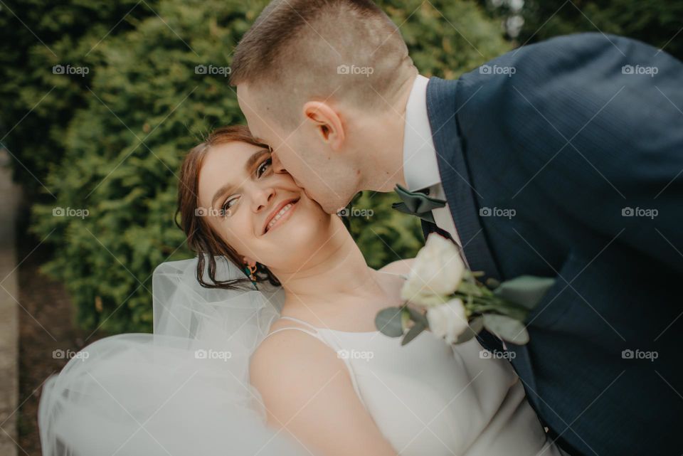 A happy photo of a tender kiss of the bride and groom during a photo shoot