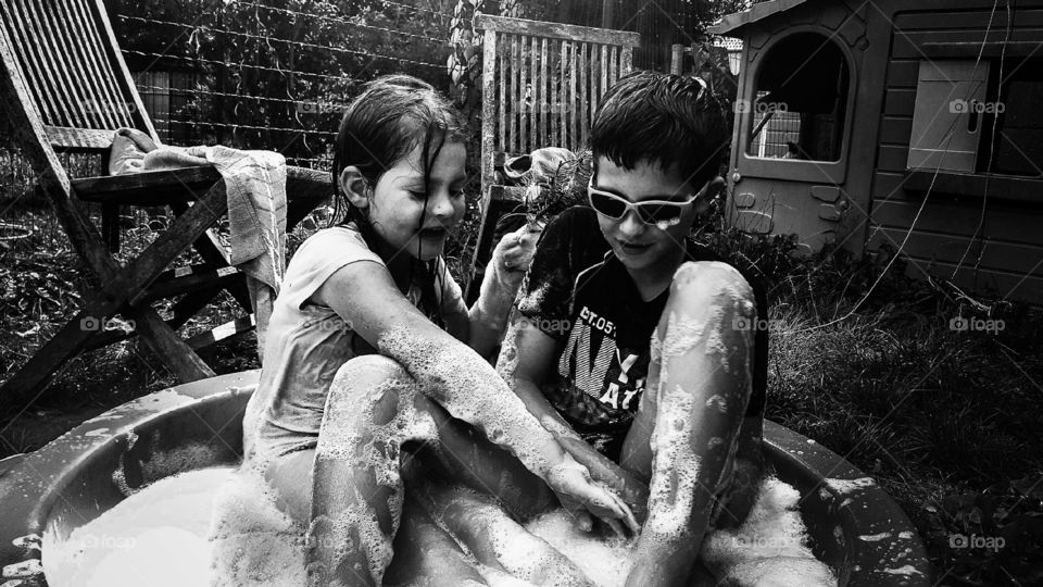 My children playing In the garden with water and soap in the summer