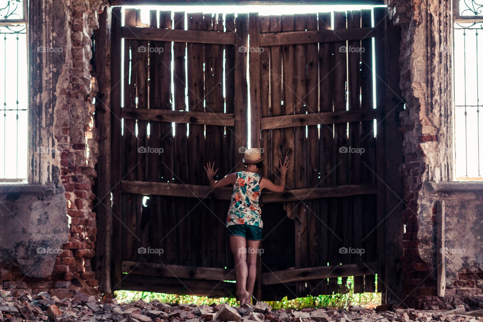Rear view of a girl looking from closed wooden door