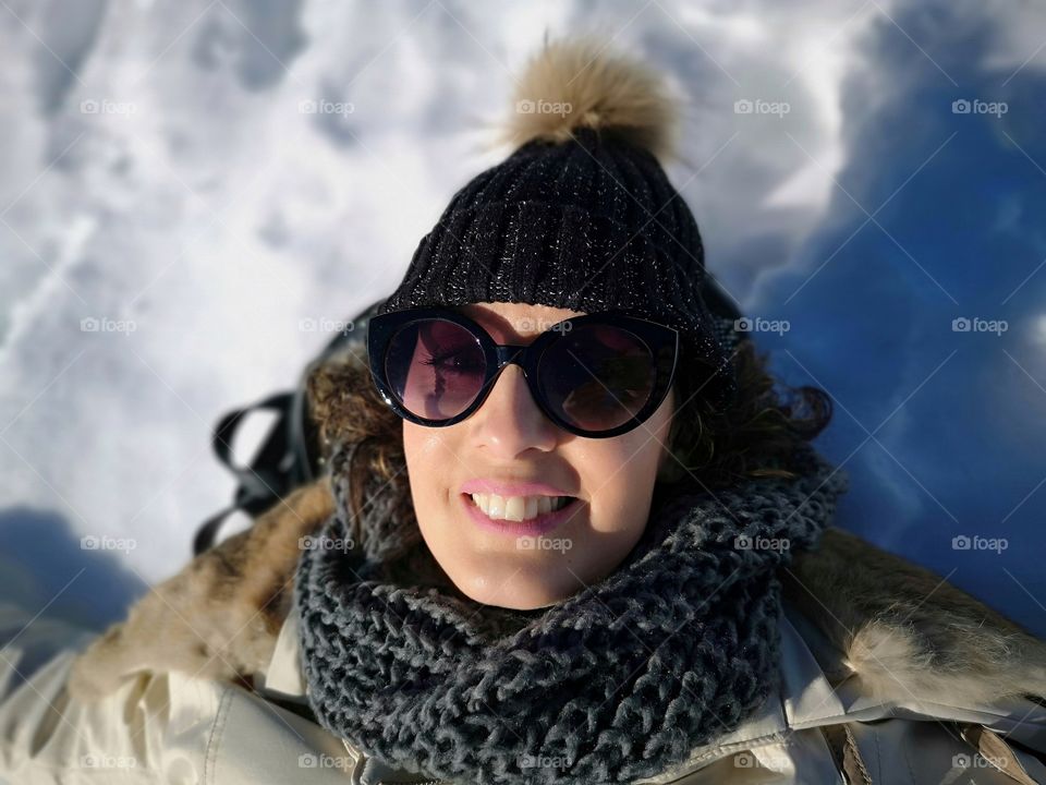 woman with scarf and hat lying on the snow in the mountains