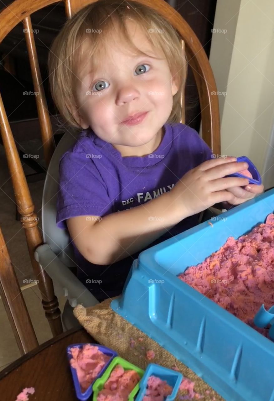 Toddler girl playing inside with sand toy