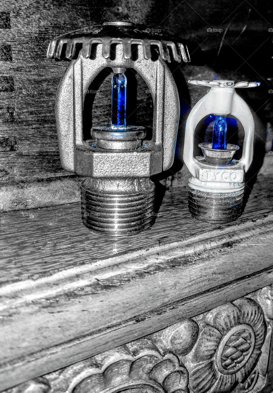 This is a close up of two different indoor sprinkler fuse heads. Once a certain temp is reached, the liquid breaks the glass &turns the sprinkler in to put out a fire. I think they're interesting&look cool beside the wood cut outs.
