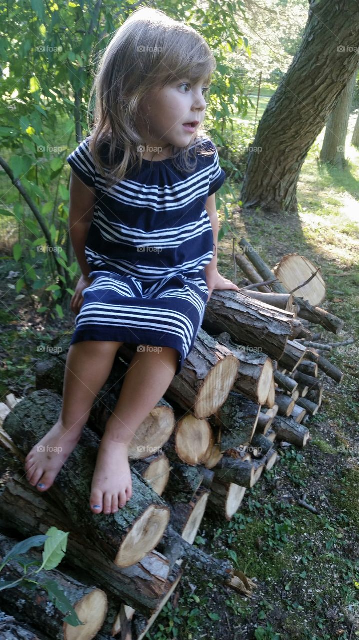 Girl sitting on wooden stack