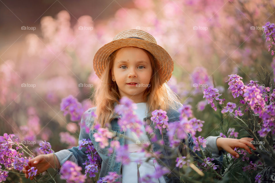 Cute little girl portrait in blossom meadow at sunset 