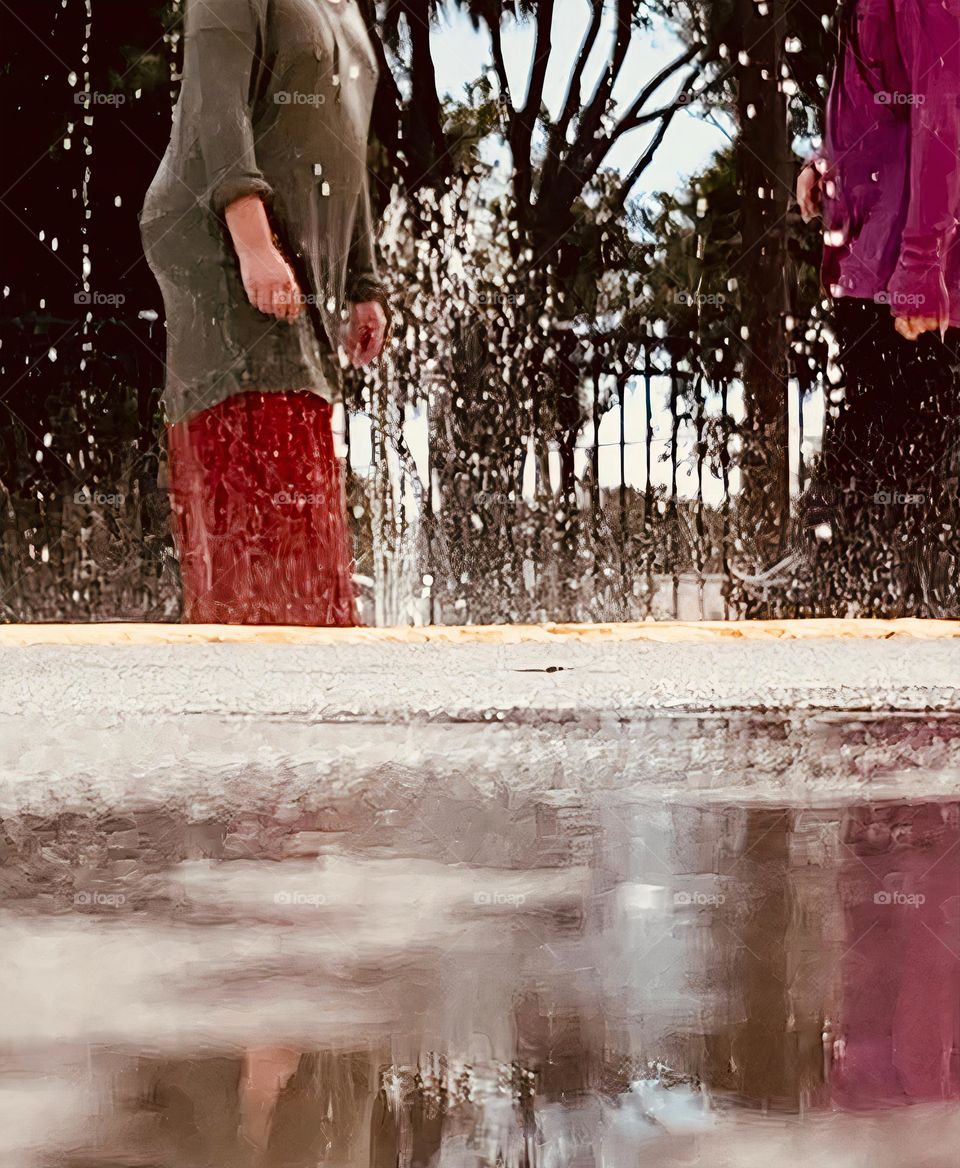 Children having lots of fun in the water at the colorful kids splash pad at the city park for children during a really warm day in Florida.