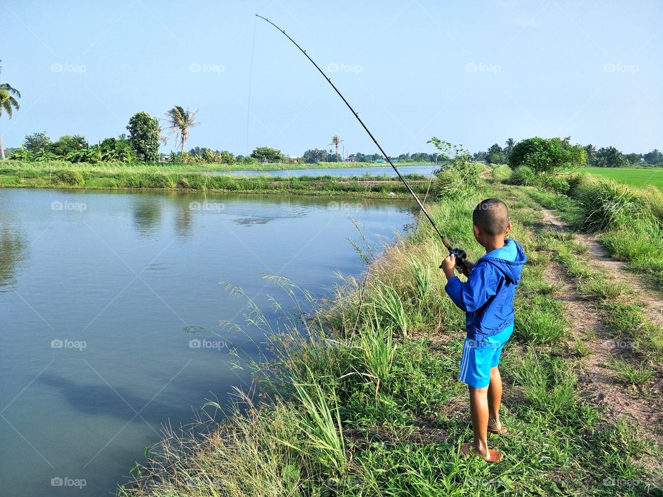 The boy is fishing in pond.
