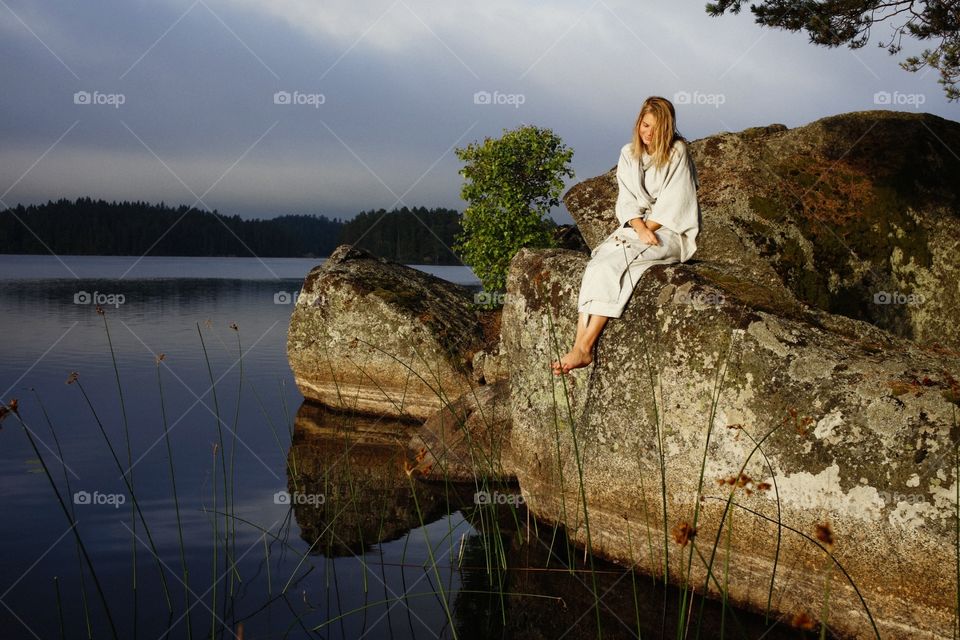 Woman enjoying sunrise by glassy lake in Swedish Nordic forest